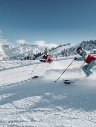 Skiers in beautiful sunshine and dream snow conditions in the Hochkönig region